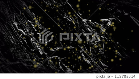 Image of yellow particles floating over light on moving shiny black plastic 115708314