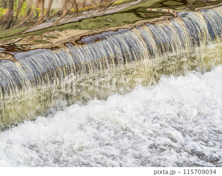 A small flat cascade in a calm river 115709034