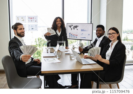 Diverse business team celebrating financial success with money in office 115709476