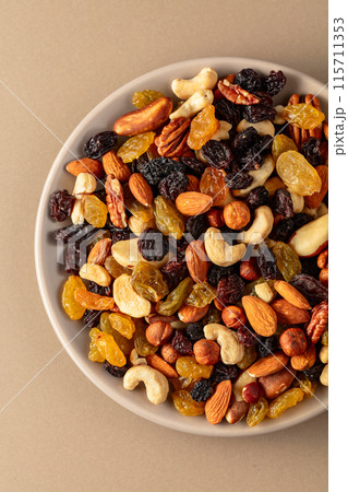 Mix of dried nuts and raisins on a beige background. Mix of dried nuts and raisins on a beige background. 115711353