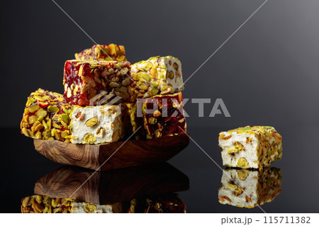 Turkish delight in a wooden dish on a black reflective background. Turkish delight in a wooden dish on a black reflective background. 115711382