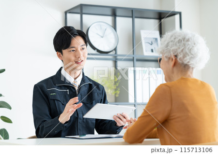 シニアの女性に営業する工務店の若い男性 115713106