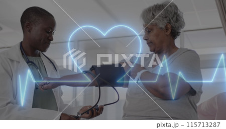 Image of cardiograph and heart over diverse senior female patient and doctor taking pressure 115713287