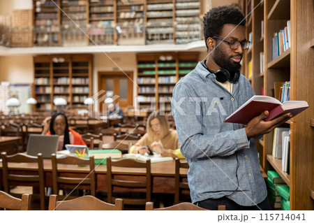 African american young man in the library looking busy and involved 115714041