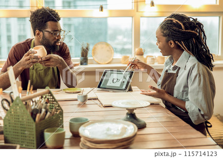Dark-skinned woman with dreads conducting a ceramics workshop 115714123