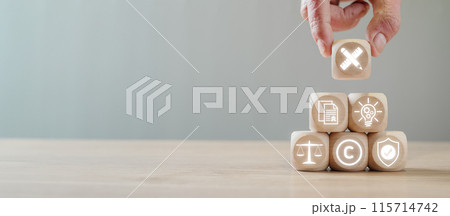 Wooden blocks with icons symbolizing intellectual property concepts like copyright, patent, trademark, and legal protection. 115714742