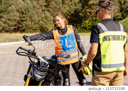 A woman in a motorcycle safety vest is being instructed by a man in a bright yellow vest. Concept of learning and guidance 115715100