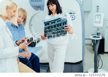 Supportive female doctor soothing woman patient, discussing test result in emergency room. Doctor examine MRI picture. Compassionate physician supporting stressed patient concept. Supportive female doctor soothing woman patient, discussing test result in emergency room. Doctor examine MRI picture. Compassionate physician supporting stressed patient concept. 115715176