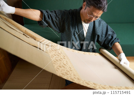 掛軸を広げて確認する和服の男性　鑑定士　古物商　収集家　イメージ 115715491