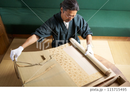 掛軸を広げて確認する和服の男性　鑑定士　古物商　収集家　イメージ 115715495