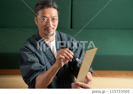 短冊に文字を書く和服の男性 115715505