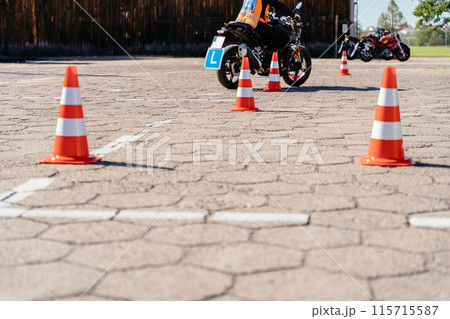 Riding between cones, lesson in motorcycle school. Close up. Letter L sign. Moto school track driving school. 115715587