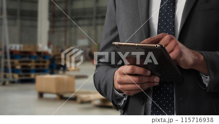Man in suit with dotted tie uses tablet in office. 115716938