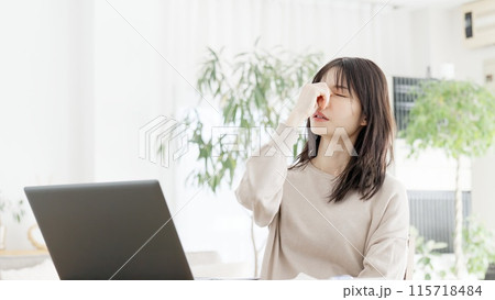 パソコン作業に目の疲れを感じる女性 115718484