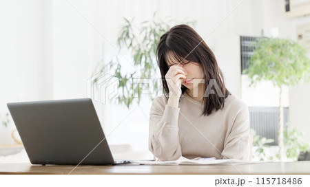 パソコン作業に目の疲れを感じる女性 115718486