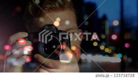 Caucasian male photographer clicking pictures with digital camera against night city traffic Caucasian male photographer clicking pictures with digital camera against night city traffic 115718728