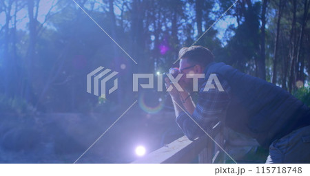 Spots of light against caucasian male photographer clicking pictures with digital camera outdoors 115718748