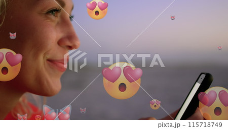 Image of emoticons over profile of happy biracial woman using smartphone at beach 115718749