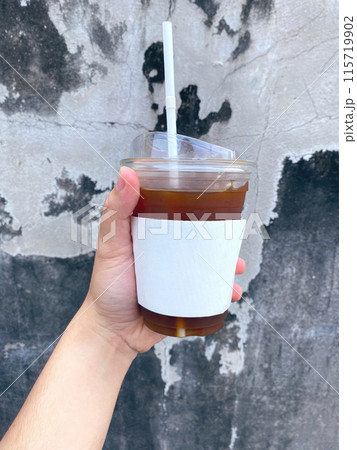 A close-up photo of a hand holding a mug of coffee 115719902