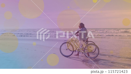 Senior couple celebrates Pedal Day at beach with bicycles. 115721423