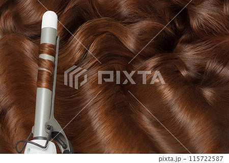 Hot curling tongs iron on bright colorful wavy hair. Coiffure, beauty salon and hair styling concept 115722587