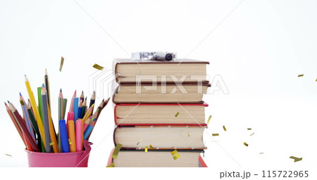 Image of confetti falling over colour pencils and stack of books 115722965