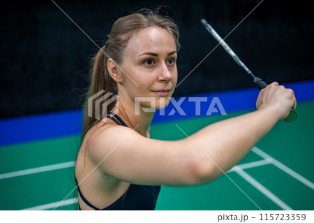 Sports young woman with racket and shuttlecock is posing before playing in badminton on inside court Sports young woman with racket and shuttlecock is posing before playing in badminton on inside court 115723359