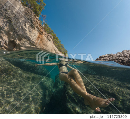 Young female on holidays enjoy floating on a crystal clear water beach of Antalya Turkey. Asian beautiful woman swimming with open arms. Relax and tranquility. Travel and Holiday concept. 115725809