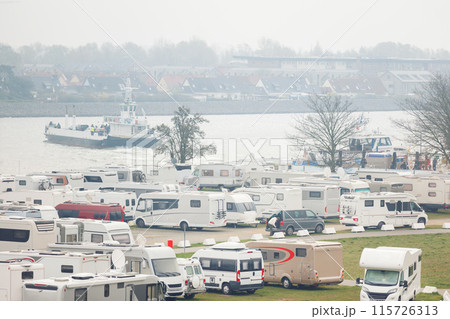 RV camper van parking place at Warnemunde Rostock harbor canal cruise liner pier ferry vessel ship background. Many recreational vehicle parked Germany port harbor foggy day. Travel tourism adventure RV camper van parking place at Warnemunde Rostock harbor canal cruise liner pier ferry vessel ship background. Many recreational vehicle parked Germany port harbor foggy day. Travel tourism adventure 115726313