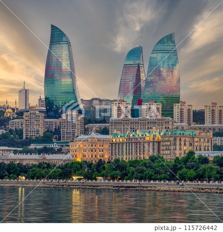 Night view of the iconic illuminated Flame Towers in Baku, Azerbaijan, reflected in the calm waters of the Caspian Sea 115726442