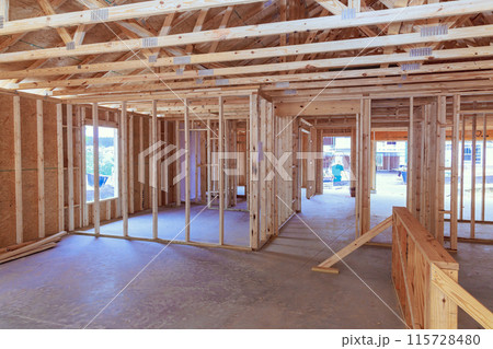 An unfinished residential home under construction with wood framing beam supporting it An unfinished residential home under construction with wood framing beam supporting it 115728480