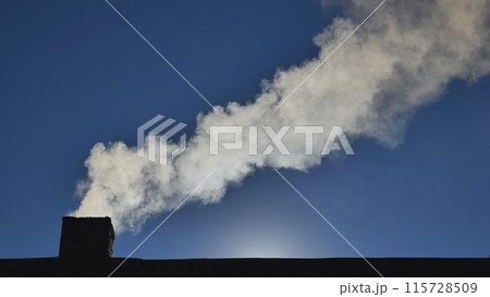 Silhouette of smoke against blue sky from the chimney of a village house. Silhouette of smoke against blue sky from the chimney of a village house. 115728509