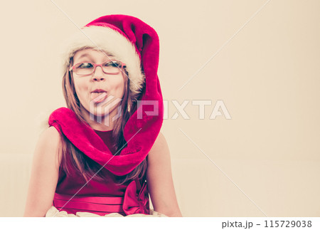 Girl in santa hat making silly face 115729038