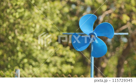 A blue vane weathervane spins in the wind in the summer. 115729345