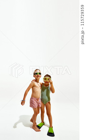 Poster. Boy and girl, ready for swim, pose together in swimwear against white studio background with copy space. 115729359
