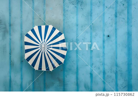 Aerial view of a swimming pool with a blue and white striped umbrella by the side, depicting a summer vacation concept. Minimalistic Aerial view of a swimming pool with a blue and white striped umbrella by the side, depicting a summer vacation concept. Minimalistic 115730862
