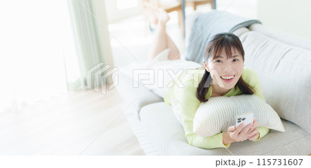 スマホを持って寝転がっている若い女性 115731607