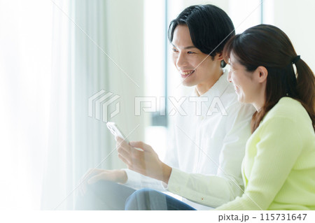スマホを見る若い夫婦 115731647