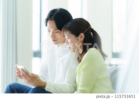 スマホを見る若い夫婦 115731651