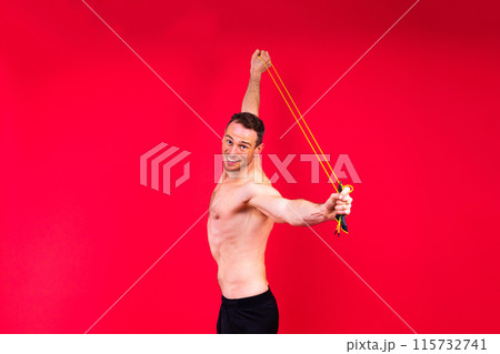 Full length portrait of a young man exercising with a skipping rope and looking at the camera 115732741
