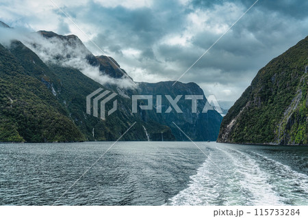 Sightseeing cruise with majestic mountain and waterfall flowing in Milford Sound, New Zealand 115733284