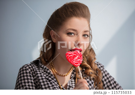 Beautiful girl with a red candy in the form of a heart 115735033