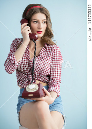 Woman in the style of the fifties. Beautiful retro woman with an old telephone. 115735336
