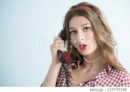 Woman in the style of the fifties. Beautiful retro woman holding a telephone receiver. Woman in the style of the fifties. Beautiful retro woman holding a telephone receiver. 115735340
