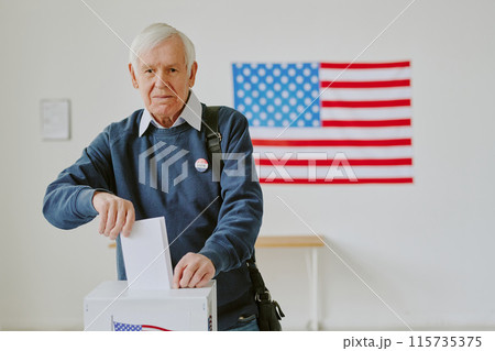 Medium shot of elderly Caucasian male citizen casting vote at polling station on election day, copy space 115735375