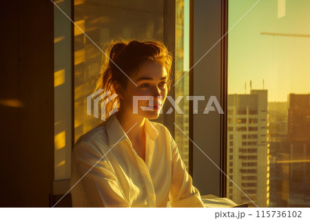 Sunlit Success: Woman in Office Amid Evening Glow 115736102