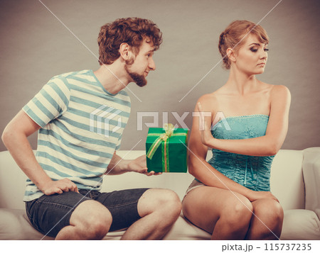 Young man giving offended woman gift box Young man giving offended woman gift box 115737235