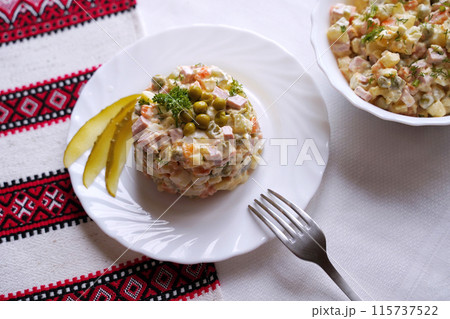 Olivier salad, traditional salad dish of post Soviet cuisine. Traditional Ukrainian food on the table with embroidered tablecloth. 115737522