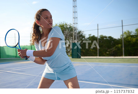 Focused woman playing tennis on an outdoor court Focused woman playing tennis on an outdoor court 115737832
