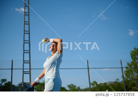 Female tennis player smiling on court under blue sky 115737858